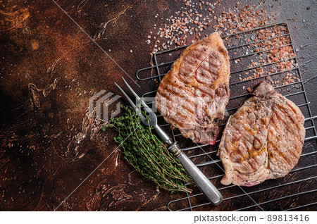 BBQ Grilled Pork loin steaks from neck fillet meat on grill. Dark background. Top view. Copy space BBQ Grilled Pork loin steaks from neck fillet meat on grill. Dark background. Top view. Copy space 89813416