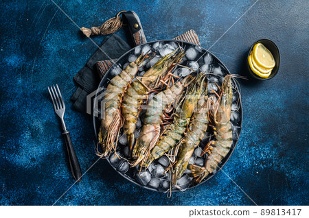 Giant Black tiger prawns shrimps on a plate with ice. Raw Seafood. Blue background. Top view Giant Black tiger prawns shrimps on a plate with ice. Raw Seafood. Blue background. Top view 89813417