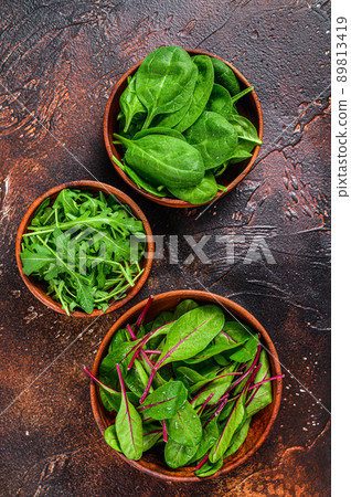 Mix Salad leafs, Arugula, Spinach and swiis Chard in wooden bowls. Dark background. Top view Mix Salad leafs, Arugula, Spinach and swiis Chard in wooden bowls. Dark background. Top view 89813419