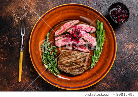 Fried sliced flank or bavette beef meat steak on a plate. Dark background. Top view 89813495