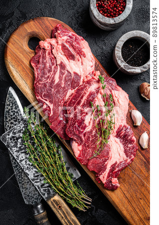 Butcher marbled meat Steaks on wooden cutting board, raw beef rib-eye steaks. Black background. Top view Butcher marbled meat Steaks on wooden cutting board, raw beef rib-eye steaks. Black background. Top view 89813574