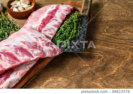 Raw pork rack spare ribs with spices, garlic cloves and thyme. Wooden background. Top view. Copy space 89813578