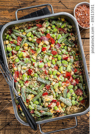 Mix of frozen raw vegetables and quinoa in a kitchen tray. Wooden background. Top view Mix of frozen raw vegetables and quinoa in a kitchen tray. Wooden background. Top view 89813581