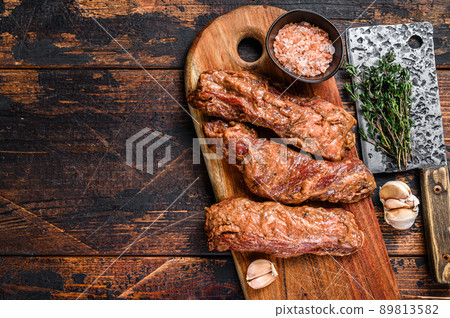 Raw Marinated skirt steaks in bbq sauce on a wooden cutting board with herbs. Dark wooden background. Top view. Copy space Raw Marinated skirt steaks in bbq sauce on a wooden cutting board with herbs. Dark wooden background. Top view. Copy space 89813582