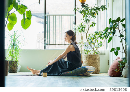 A woman relaxing surrounded by foliage plants 89813608