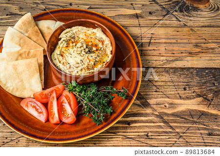 Fresh Hummus with pita bread, tomato and parsley on a rustic plate. wooden background. Top view. Copy space 89813684