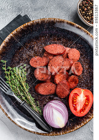 Fried sausage sucuk from beef meat on a plate with herbs. White background. Top view Fried sausage sucuk from beef meat on a plate with herbs. White background. Top view 89813867