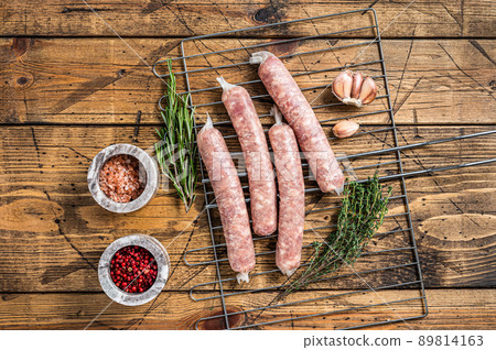 Raw sausages - Bratwurst with pork meat on a griil. Wooden background. Top view 89814163