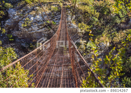 Sights of Montenegro. Landmark Old rusty bridge. Attraction Long extreme suspension iron bridge across the river Moraca. Montenegro Sights of Montenegro. Landmark Old rusty bridge. Attraction Long extreme suspension iron bridge across the river Moraca. Montenegro 89814267