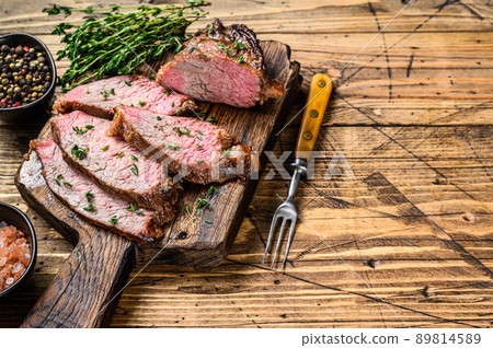 Rare slices of Roast beef sirloin tri tip steak bbq on a wooden cutting board. wooden background. Top view. Copy space 89814589