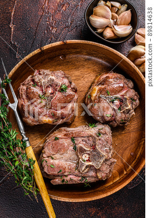 Fried lamb neck meat steaks in a wooden plate with herbs. Dark background. Top view Fried lamb neck meat steaks in a wooden plate with herbs. Dark background. Top view 89814638