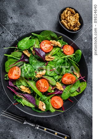 Vegetarian salad with mix leaves mangold, swiss chard, spinach, arugula and nuts in a salad bowl. Black background. Top view Vegetarian salad with mix leaves mangold, swiss chard, spinach, arugula and nuts in a salad bowl. Black background. Top view 89814640