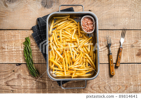 Fried French fries potatoes with salt in kitchen tray. Wooden background. Top view Fried French fries potatoes with salt in kitchen tray. Wooden background. Top view 89814641