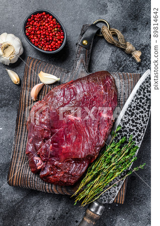 Venison raw deer meat on a cuuting board with herbs. Black background. Top view 89814642
