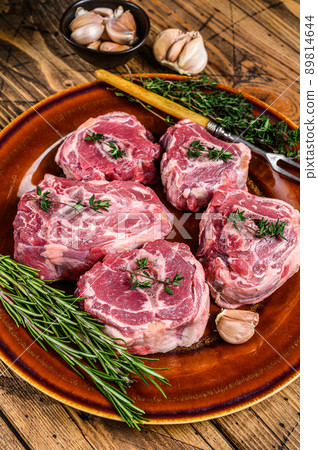 Mutton lamb neck meat on a rustic plate with thyme and rosemary. wooden background. Top view Mutton lamb neck meat on a rustic plate with thyme and rosemary. wooden background. Top view 89814644
