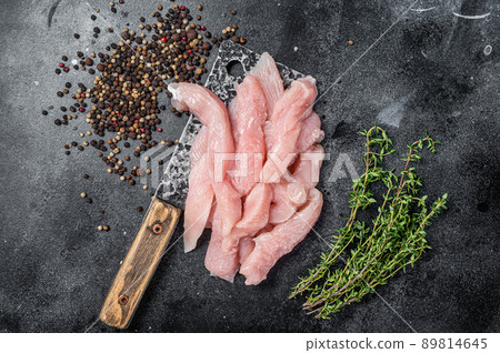 Slices of raw poultry meat on a butcher board with meat cleaver, chicken breast. Black background. Top view Slices of raw poultry meat on a butcher board with meat cleaver, chicken breast. Black background. Top view 89814645