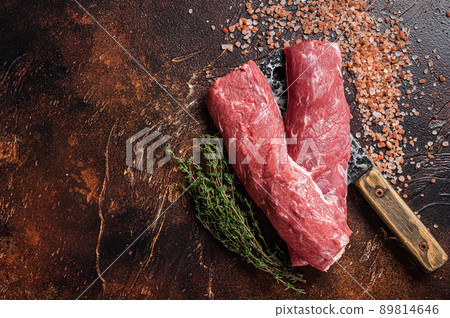 Uncooked lamb loin fillet, Mutton raw meat on butcher cleaver. Dark background. Top view. Copy space Uncooked lamb loin fillet, Mutton raw meat on butcher cleaver. Dark background. Top view. Copy space 89814646