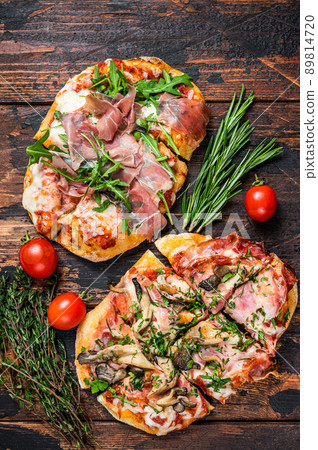 Sliced pizza with prosciutto parma ham, arugula and parmesan cheese. Dark wooden background. Top view Sliced pizza with prosciutto parma ham, arugula and parmesan cheese. Dark wooden background. Top view 89814720