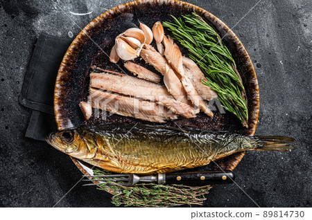 Hot Smoked herring fish fillet on rustic plate with thyme and rosemary. Black background. Top view 89814730