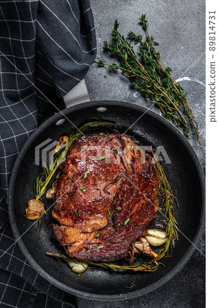 Roasted rib eye steak, ribeye beef meat in a pan. Black background. Top view 89814731
