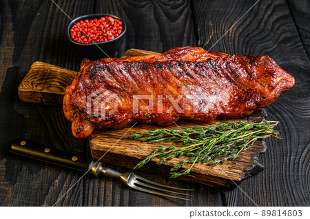 Grilled in bbq sauce veal short spare rib meat on wooden cutting board. Black wooden background. Top view 89814803