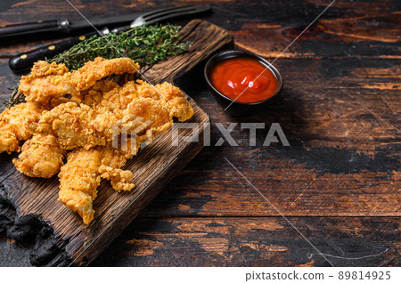 Chicken strips on a wooden cutting Board. Dark Wooden background. Top view. Copy space 89814925