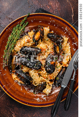 Seafood Mafaldine pasta with mussels and tomato sauce in a rustic plate. Dark background. Top view Seafood Mafaldine pasta with mussels and tomato sauce in a rustic plate. Dark background. Top view 89814930