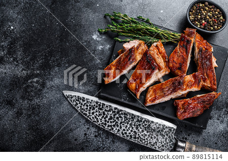 Sliced Grilled veal short spare rib meat with butcher knife. Black background. Top view. Copy space Sliced Grilled veal short spare rib meat with butcher knife. Black background. Top view. Copy space 89815114