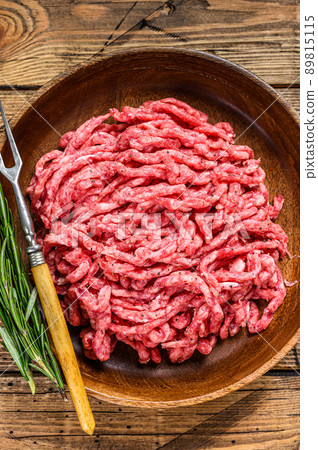 Raw mince lamb, ground mutton meat with herbs on a plate. Wooden background. Top view Raw mince lamb, ground mutton meat with herbs on a plate. Wooden background. Top view 89815115