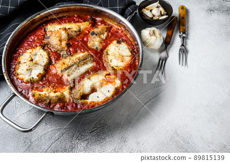 Baked grenadier macrurus white fish with tomato in a pan. White Wooden background. Top view. Copy space Baked grenadier macrurus white fish with tomato in a pan. White Wooden background. Top view. Copy space 89815139