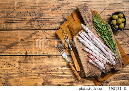 Spanish dry salami sausage Fuet with rosemary on wooden cutting board. Wooden background. Top view. Copy space 89815148