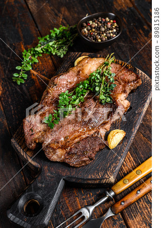 Grilled Chuck eye roll beef meat steak on a cutting board. Dark wooden background. Top view 89815186