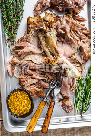 Baked pork knuckle eisbein meat on a baking pan with herbs. Wooden background. Top view Baked pork knuckle eisbein meat on a baking pan with herbs. Wooden background. Top view 89815276