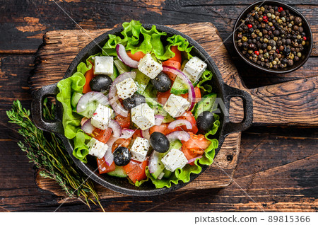 Greek salad with fresh vegetables and feta cheese in a pan. Dark Wooden background. Top view 89815366