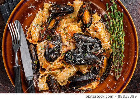 Seafood Mafaldine pasta with mussels and tomato sauce in a rustic plate. Dark background. Top view Seafood Mafaldine pasta with mussels and tomato sauce in a rustic plate. Dark background. Top view 89815389