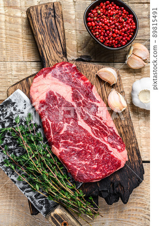 Prime rib eye raw beef meat steak on a butcher wooden cutting board with cleaver. wooden background. Top view Prime rib eye raw beef meat steak on a butcher wooden cutting board with cleaver. wooden background. Top view 89815491