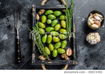 Fresh Green olives in wooden tray with thyme. Black background. Top view Fresh Green olives in wooden tray with thyme. Black background. Top view 89815492