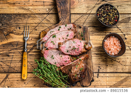 Rare slices of Roast beef sirloin tri tip steak bbq on a wooden cutting board. wooden background. Top view Rare slices of Roast beef sirloin tri tip steak bbq on a wooden cutting board. wooden background. Top view 89815536