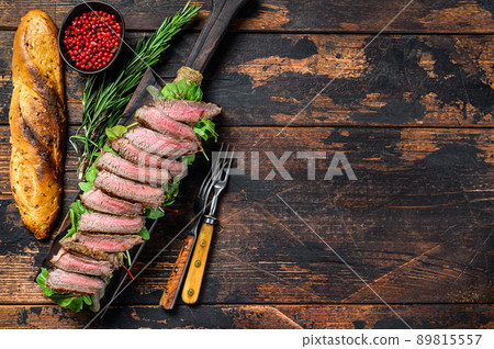 Flank Steak baguette sandwich with arugula on a cutting board. Dark wooden background. Top view. Copy space 89815557