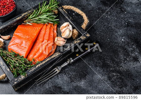 Smoked sliced salmon fillet in a wooden tray with herbs. Black background. Top view. Copy space Smoked sliced salmon fillet in a wooden tray with herbs. Black background. Top view. Copy space 89815596