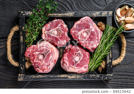 Raw lamb neck meat on a butcher table with knife. Black wooden background. Top view 89815642