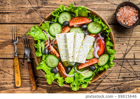 Greek salad with fresh vegetables and feta cheese. Wooden background. Top view Greek salad with fresh vegetables and feta cheese. Wooden background. Top view 89815646