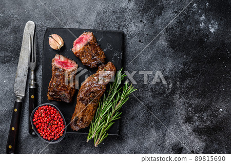 Grilled brisket steaks in bbq sauce on a marble board. Black background. Top view. Copy space Grilled brisket steaks in bbq sauce on a marble board. Black background. Top view. Copy space 89815690