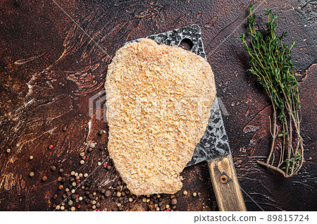 Pork Raw Escalope or schnitzel on a meat cleaver with herbs. Dark background. Top view Pork Raw Escalope or schnitzel on a meat cleaver with herbs. Dark background. Top view 89815724