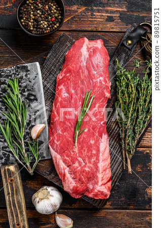 Raw flank beef meat steak on a cutting board with cleaver. Dark wooden background. Top view 89815751