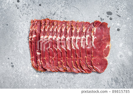 Turkish bacon Pastrami beef meat. Gray background. Top view Turkish bacon Pastrami beef meat. Gray background. Top view 89815785