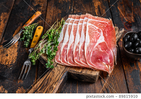 Traditional Spanish sliced Jamon Serrano ham on a cutting board. Dark wooden background. Top view 89815910