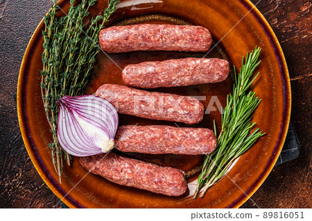 Raw kofta meat kebabs sausages on a plate with herbs. Dark background. Top view 89816051