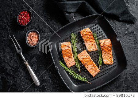 Roasted salmon fillets steaks on grill skillet. Black background. Top view Roasted salmon fillets steaks on grill skillet. Black background. Top view 89816178