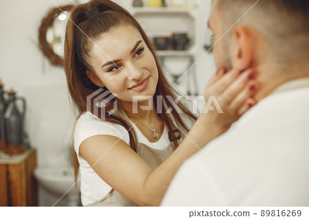 Mutual creative work. Young beautiful couple in casual clothes and aprons. People creating a bowl on a pottery wheel in a clay studio. Mutual creative work. Young beautiful couple in casual clothes and aprons. People creating a bowl on a pottery wheel in a clay studio. 89816269
